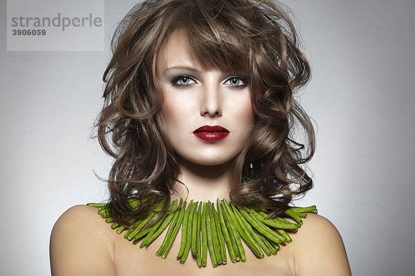 Portrait einer jungen Frau mit grünen Bohnen als Halskette  Schmuck