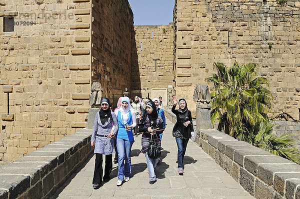 Junge Frauen mit Kopftuch am Eingang  römisches Theater in Bosra  Syrien  Asien