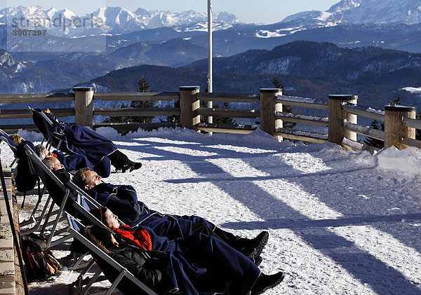 Menschen genießen die Wintersonne auf der Terrasse eines Bergrestaurants auf der Kampenwand  Chiemgau  Oberbayern  Deutschland  Europa