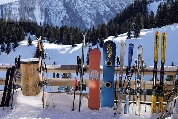 Skier und Snowboards lehnen an einem Holzzaun  Kampenwand  Chiemgau  Oberbayern  Deutschland  Europa