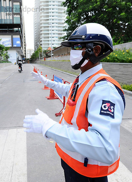Mann mit Schutzmaske regelt den Verkehr  Thailand  Asien
