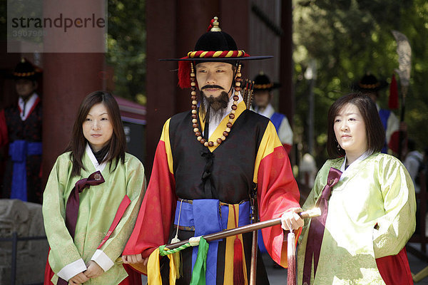 Junge Frauen posieren mit einem der Wächter vor dem Königspalast Deoksugung  Palast der rechtschaffenden Langlebigkeit  in der koreanischen Hauptstadt Seoul  Süd-Korea  Asien
