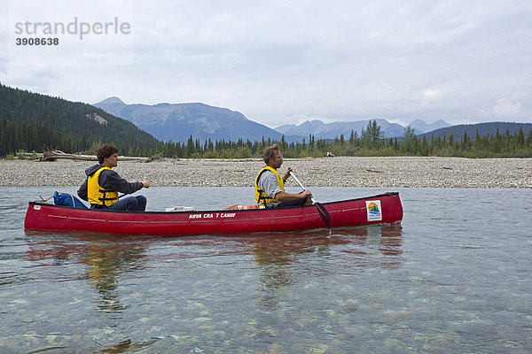 Zwei Männer in einem Kanu  Kanufahren auf dem oberen Liard River Fluß  klares  seichtes Wasser  dahinter das Pelly Mountains Gebirge  Yukon Territory  Kanada