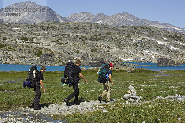 Gruppe von Wanderern mit Rucksack  auf dem historischen Chilkoot Pass  Chilkoot Trail  Inuit Markierung  Inukshuk Steinhaufen  Crater Lake dahinter  alpine Tundra  Yukon Territorium  British Columbia  BC  Kanada