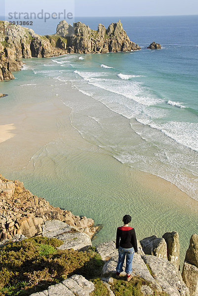 Frau schaut auf Wellen und Strand  Aussichtspunkt  Porthcurno Beach  Pednvounder Beach  Logan Rock  Südküste  Cornwall  England  Großbritannien  Europa