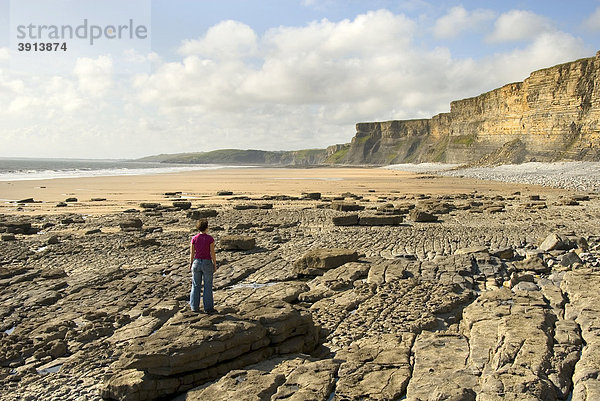 Frau auf Stein schaut auf Strand und Klippen  Küste  Nash Point  Glamorgan Heritage Coast  Südwales  Wales  Großbritannien  Europa