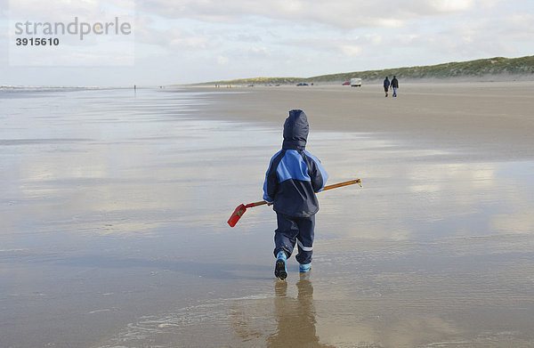 Kleiner Junge  2 Jahre  läuft mit einer Schaufel über den Nordseestrand  Vejers Strand  Jütland  Dänemark  Europa