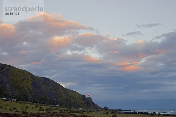 Farbenprächtige Wolken im Sonnenuntergang über dem Cape Palliser Leuchtturm an der Cook Strait  Cookstraße  an der Südspitze der Nordinsel  Neuseeland