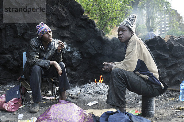 Obdachlose Immigranten aus Mosambik konsumieren Drogen  Marihuana  und wärmen sich am frühen Morgen an einem Feuer im Park Pullinger Kop  Stadtteil Hillbrow  sozialer Brennpunkt im Zentrum von Johannesbug  Südafrika  Afrika