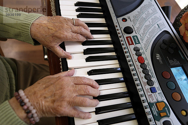 Eine Seniorin hat ihr Instrument ins Altenpflegeheim mit gebracht und spielt auf dem elektrischen Klavier
