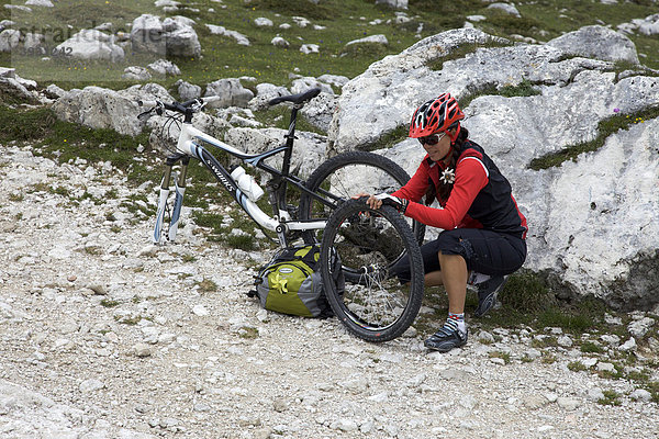 Mountainbike-Fahrerin mit Reifenpanne repariert Vorderrad