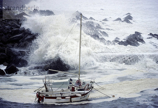 Hohe Wellen schlagen über Felsen und kleine Boote  stürmische See an der bretonischen Küste  Orkan  FinistËre  Bretagne  Frankreich  Europa