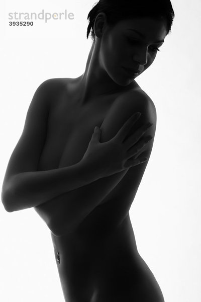 Silhouette einer nackt dastehenden jungen Frau mit Blick über ihre Schulter