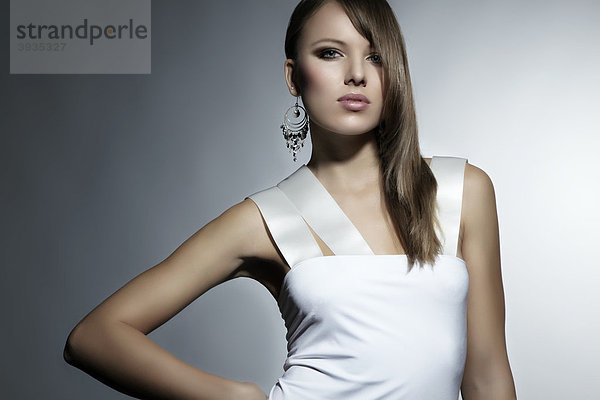 Portrait einer jungen Frau im weißen Kleid  Ohrring  direkter Blick  Fashion