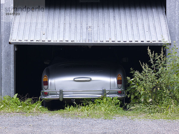Heckansicht eines VW Karmann Ghia unter halb geöffnetem Garagentor