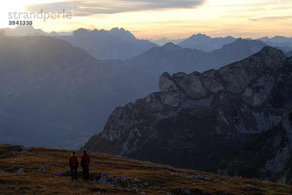 Junge Frau und Mann  Wanderer  schauen von der Heidachstellwand  2192m  in den Sonnenuntergang  Richtung Karwendel und Achensee mit Maurach  Rofan  Achensee  Tirol  Österreich  Europa