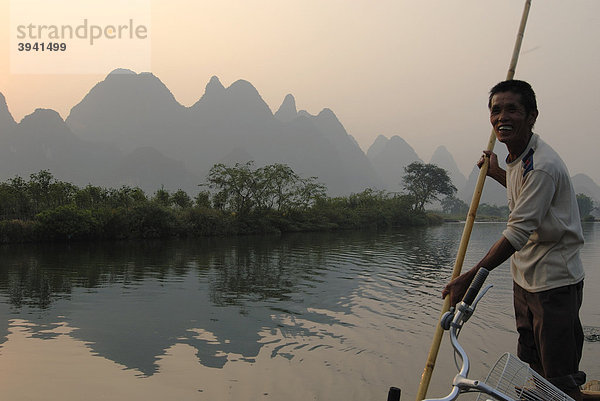 Bambusfloß mit altem chinesischem Mann mit Stake auf dem Yulong Fluss in der Karstfelsenlandschaft bei Yangshuo  Guilin  Guangxi  China  Asien