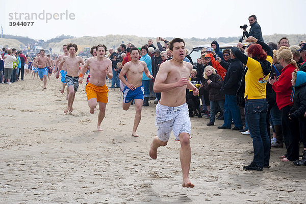 Urlauber in Badekleidung laufen beim traditionellen Paasduik Oster-Tauchen am Strand des Nordsee-Urlaubsorts Renesse und eröffnen damit die Urlaubssaison  Schouwen-Duiveland  Zeeland  Niederlande  Europa