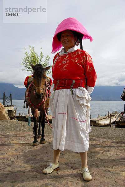 Ethnologie  Frau der Mosu Ethnie in Tracht gekleidet mit Pferd  Luoshui  Lugu Hu See  Provinz Yunnan  Volksrepublik China  Asien