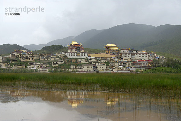 Tibetischer Buddhismus  Klosteranlage spiegelt sich im Wasser  hügelige Landschaft  Kloster Ganden Sumtseling Gompa  Zhongdian  Shangri-La  Provinz Yunnan  Volksrepublik China  Asien