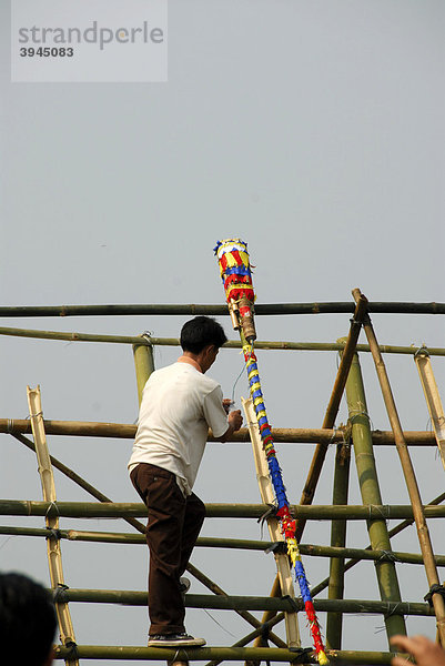 Mann legt bunt geschmückte Rakete aus Bambus auf Abschussrampe  Pi Mai  Laotisches Neujahrsfest  Volksfest  Phongsali Stadt  Phongsali Provinz  Phongsaly  Laos  Südostasien  Asien