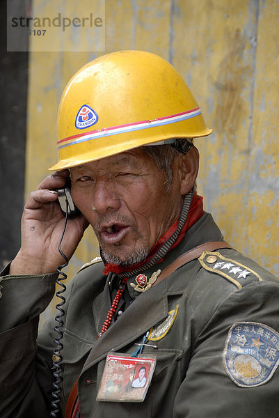 Harte Männer  Charakter  Bauarbeiter  Arbeit  chinesischer Polier mit Helm und Uniform erteilt Befehle über Funk  Lhasa  Himalaya  Autonomes Gebiet Tibet  Volksrepublik China  Asien