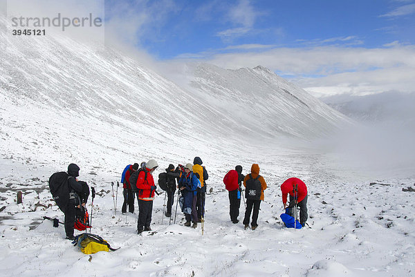 Trekking Tourismus  Gruppe Wanderer steht im Schnee  schaut ins Tal  frisch gefallener Schnee  Chitu-La Pass 5100 m  alter Pilgerweg durchs Hochgebirge von Kloster Ganden nach Samye  Himalaya  Autonomes Gebiet Tibet  Volksrepublik China  Asien