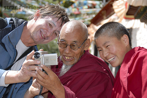 Tibetischer Buddhismus  Tourismus  Portrait  Freude  Mönch mit Brille und Spitzbart  Tourist zeigt Foto auf Digitalkamera  Einsiedelei  Kloster Yamalung bei Samye  Himalaya  Autonomes Gebiet Tibet  Volksrepublik China  Asien