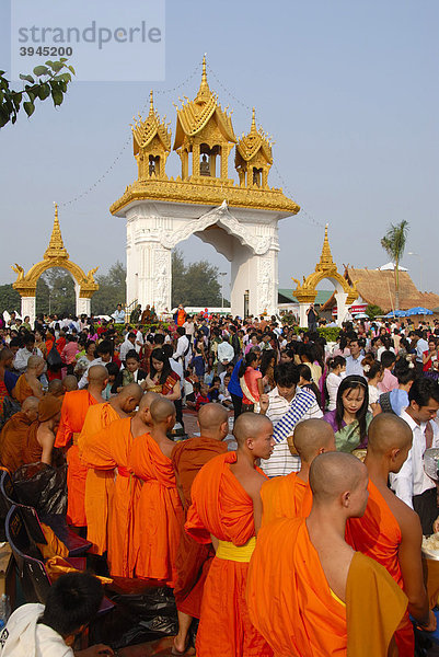 Theravada Buddhismus  That Luang Festival  Tak Bat  Gläubige  Pilger geben Almosen  Mönche stehen zusammen  Robe orange  Vientiane  Laos  Südostasien  Asien