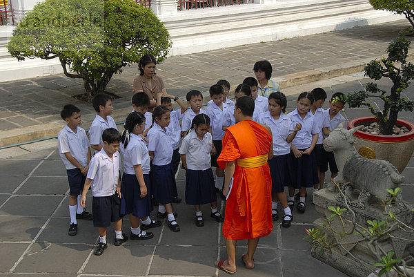 Theravada Buddhismus  Mönch als Führer einer Schulklasse  Robe orange  Schulkinder in Schuluniform  Wat Arun  Bangkok  Thailand  Südostasien  Asien