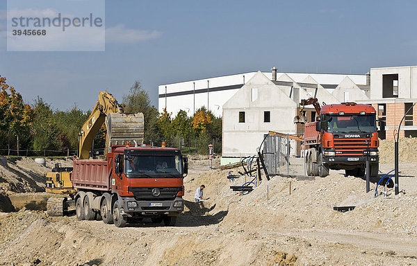 Ein LKW des Typs Mercedes Actros  links  wird mit Hilfe eines Baggers CAT 320L beladen  rechts ein LKW des Typs Scania 124C 420 auf der Baustelle Am Burgerfeld in Markt Schwaben  Bayern  Deutschland  Europa