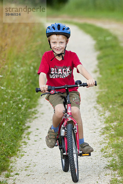 Ein Junge  7 Jahre  mit Fahrrad  auf einem Feldweg