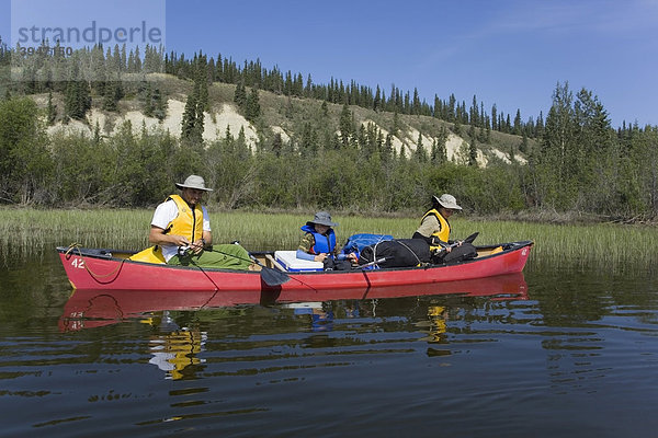Familie mit Sohn in einem Kanu beim Angeln  Teslin River High  hohe Uferböschung  Yukon Territory  Kanada