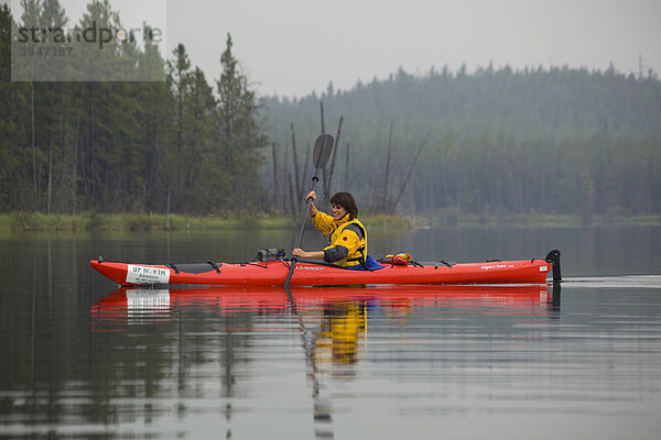 Junge Frau paddelt in einem Kajak  Kajakjahren  Snafu Lake  Yukon Territory  Kanada