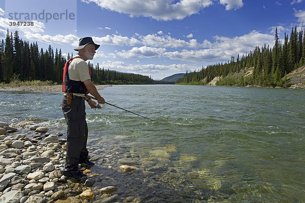 Mann angelt im oberen Liard River Fluss  klares  seichtes Wasser  hinten Berge  Yukon Territory  Kanada