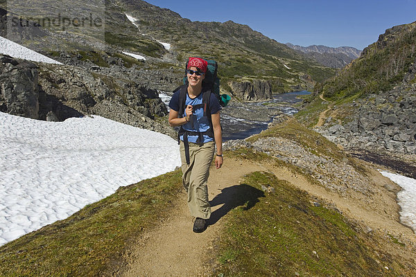 Junge Wanderin  Rucksacktour  historischer Chilkoot Pass  Chilkoot Trail Wanderweg  Schneefeld dahinter  alpine Tundra  Yukon Territory  British Columbia  BC  Kanada