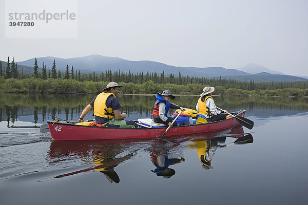 Familie mit kleinem Jungen in einem Kanu  paddeln  Kanufahren  Spiegelung auf dem ruhigen Teslin River  Yukon Territory  Kanada