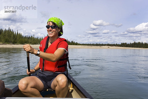 Junge Frau paddelt in einem Kajak  Lenken eines Kanus  oberer Liard River  Yukon Territory  Kanada