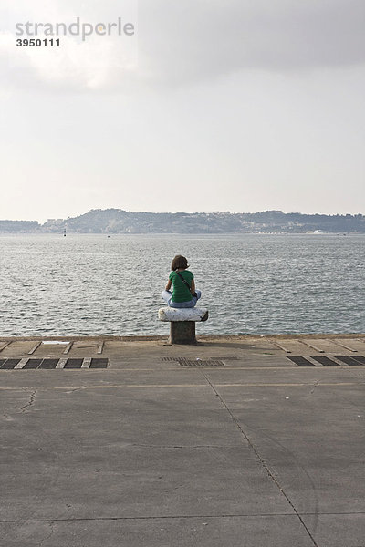 Eine Frau sitzt auf einem Poller und schaut aufs Meer im Hafen von Pozzuoli  Neapel  Kampanien  Italien  Europa