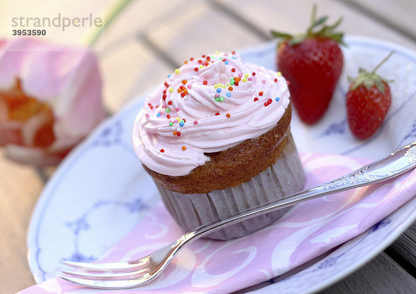 Cupcake Muffin mit Sahne  Zuckerstreuseln und Erdbeeren auf Teller