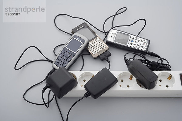 Unterschiedliche Ladegeräte diverser Mobiltelefone stecken in einer Steckdosenleiste