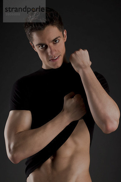Junger muskulöser Mann  Arme  hochgezogenes T-Shirt