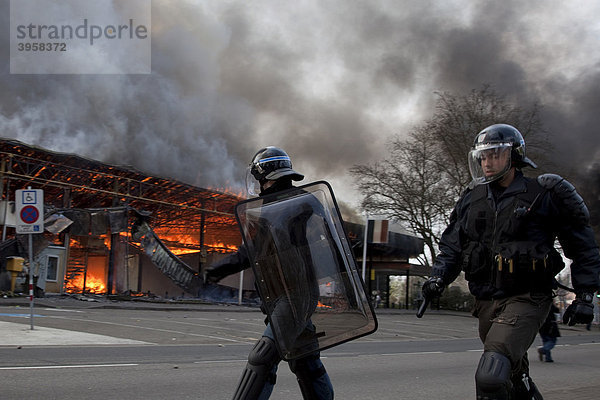Polizisten vor von Demonstranten bei Protesten gegen den NATO-Gipfel in Brand gestecktem Gebäude  Straßburg  Frankreich
