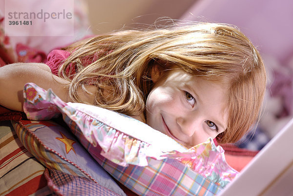 Kleines Mädchen zwischen den Kissen auf ihrem Bett  lacht
