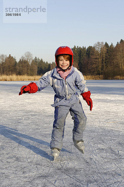 Mädchen mit Helm beim Schlittschuhlaufen auf einem Weiher