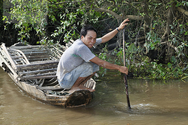 Mann rudert ein Holzboot  Mekongdelta  Vietnam  Asien