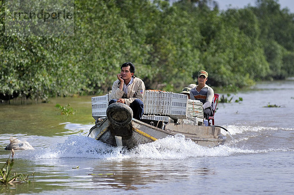 Zwei Männer fahren auf einem hölzernen Marktboot in einem Seitenkanal des Mekong  Mekongdelta  Vietnam  Asien