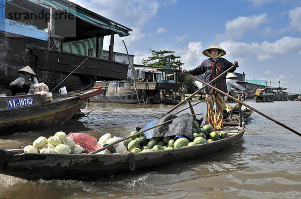 Frau mit traditionellem Hut  Kegelhut aus Palmenblättern  rudert stehend ein Holzboot am Mekong  Ladung von Obst und Gemüse  Mekongdelta  Vietnam  Asien