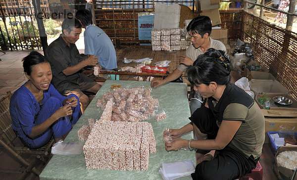Zwei Männer und zwei Frauen beim Verpacken von Puffreis-Süßigkeiten  Süßwarenfabrik  Vinh Long  Mekongdelta  Vietnam  Südostasien