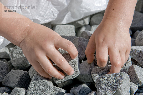 Kinderhände greifen nach Glasschaumgranulat  moderner Dämmstoff aus Altglas für die Bodendämmung